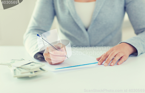 Image of close up of hands with money filling tax form