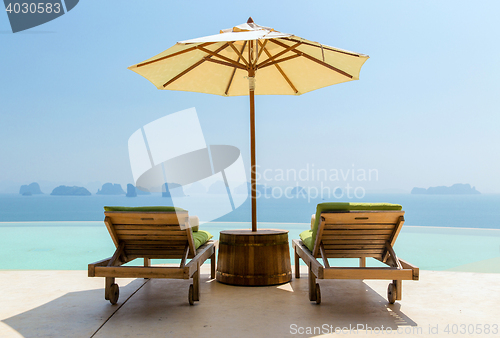 Image of infinity pool with parasol and sun beds at seaside