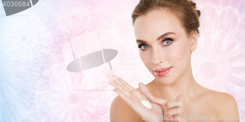 Image of happy young woman with moisturizing cream on hand