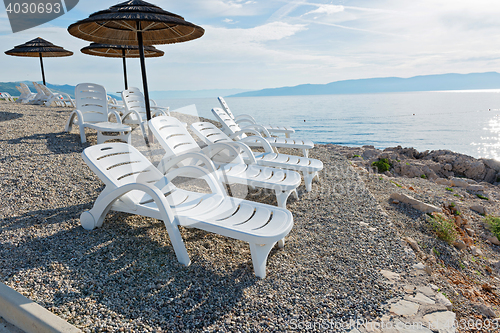 Image of Pebble beach with chaise-longues and umbrellas
