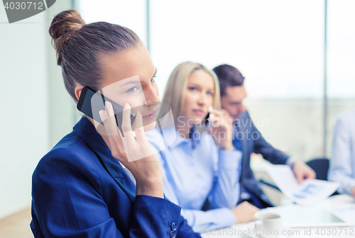 Image of smiling business team with smartphones in office