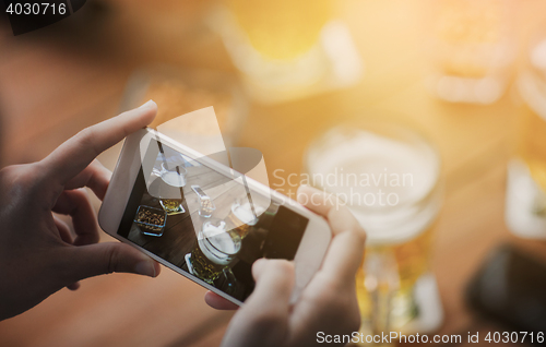 Image of close up of hands with smartphone picturing beer