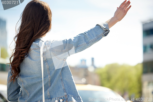 Image of young woman or girl catching taxi on city street