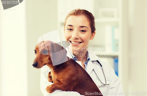 Image of happy doctor with dog at vet clinic