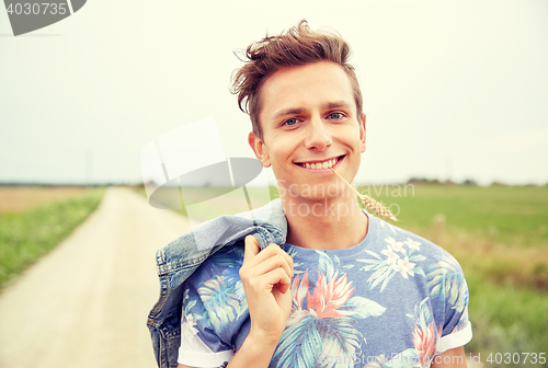 Image of smiling young hippie man on country road