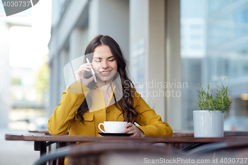 Image of happy woman calling on smartphone at city cafe