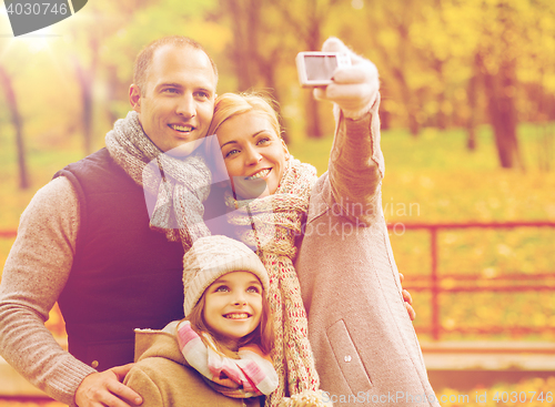 Image of happy family with camera in autumn park