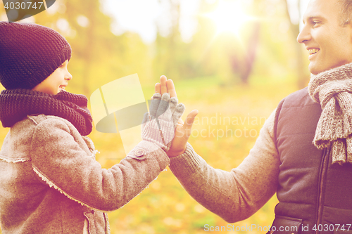 Image of happy father and son making high five in park