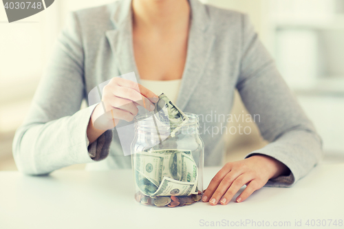 Image of close up of woman hands and dollar money in jar