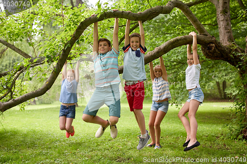 Image of happy kids hanging on tree in summer park