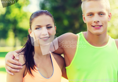 Image of happy friends or sportsmen couple hugging outdoors