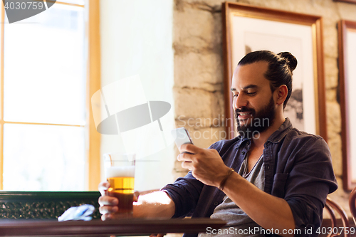 Image of man with smartphone drinking beer at bar or pub