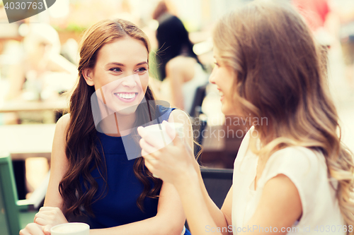 Image of smiling young women with coffee cups at cafe