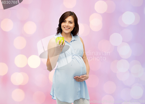 Image of happy pregnant woman holding green apple