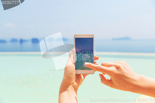 Image of close up of female hand with smartphone on beach