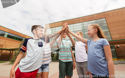 Image of group of children making high five at school yard