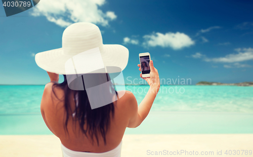 Image of woman taking selfie with smartphone on beach