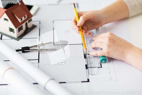 Image of close up of hands with compass measuring blueprint