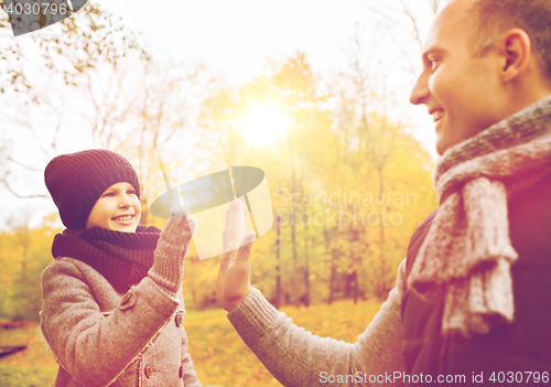 Image of happy father and son making high five in park