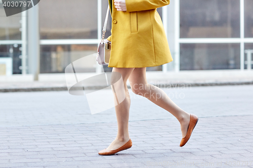 Image of young woman legs running along on city street