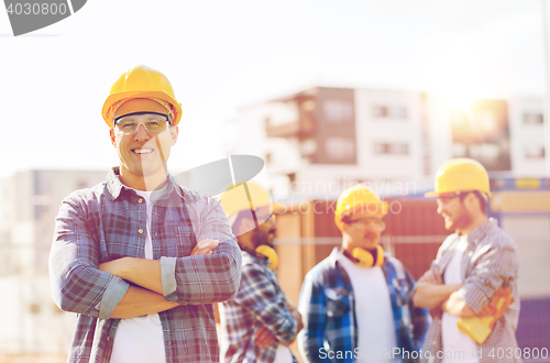 Image of group of smiling builders in hardhats outdoors