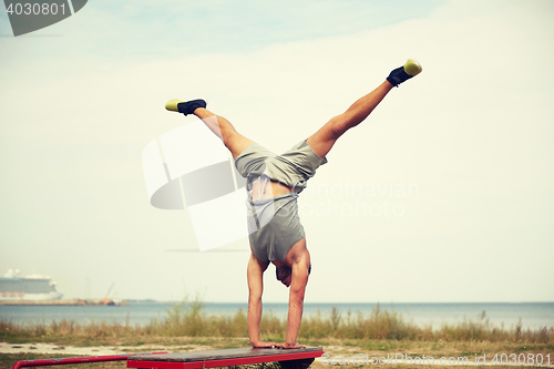 Image of young man exercising on bench outdoors