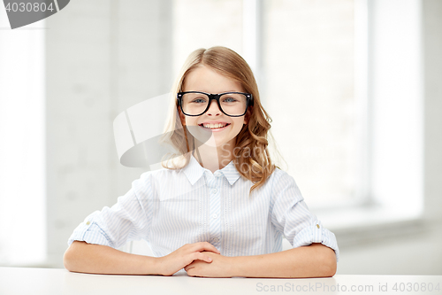 Image of happy school girl in glasses sitting at table