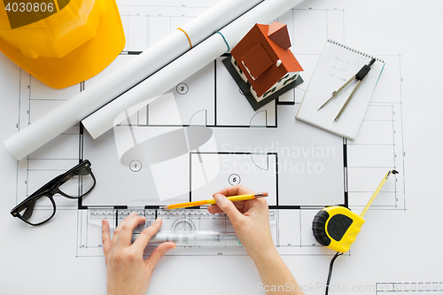 Image of close up of hands with ruler measuring blueprint