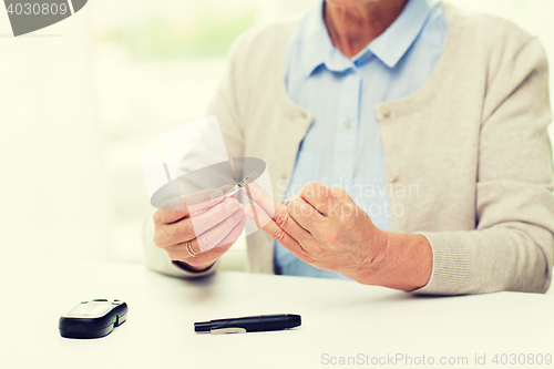 Image of senior woman with glucometer checking blood sugar