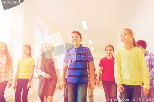 Image of group of smiling school kids walking in corridor