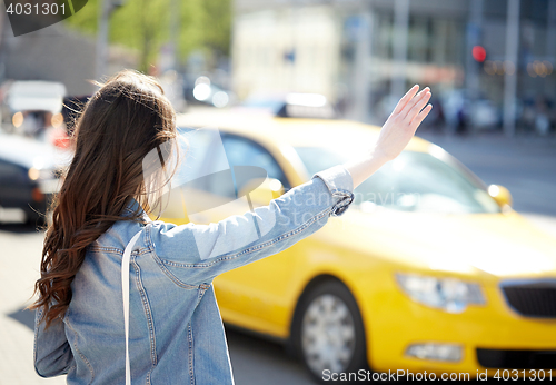 Image of young woman or girl catching taxi on city street