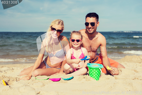 Image of happy family playing with sand toys on beach