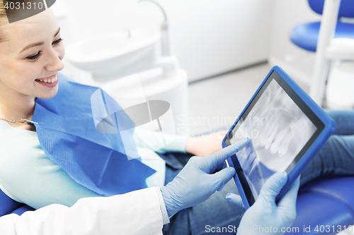 Image of dentist with teeth x-ray on tablet pc and woman