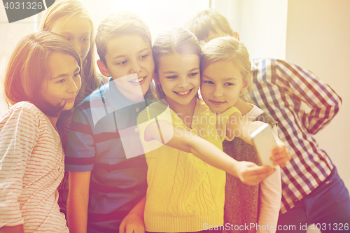 Image of group of school kids taking selfie with smartphone