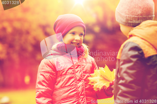 Image of little boy giving autumn maple leaves to girl