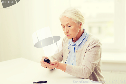 Image of senior woman with glucometer checking blood sugar