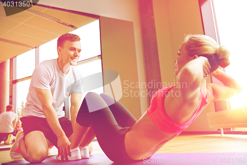 Image of woman with personal trainer doing sit ups in gym