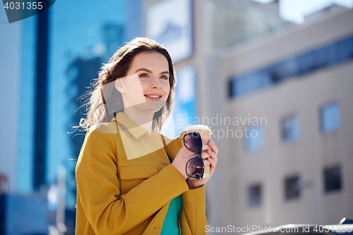 Image of happy young woman drinking coffee on city street