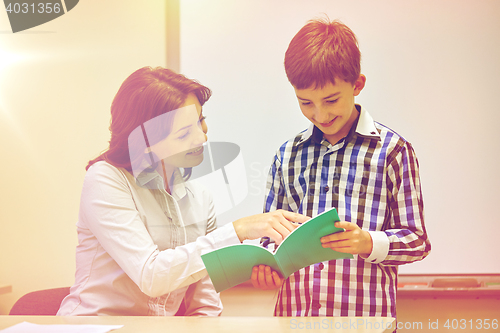 Image of school boy with notebook and teacher in classroom