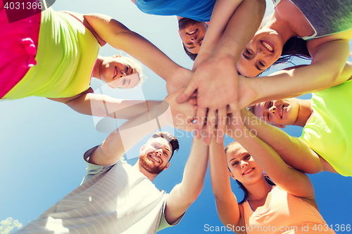 Image of group of happy friends with hands on top outdoors