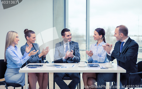 Image of business team with laptop clapping hands