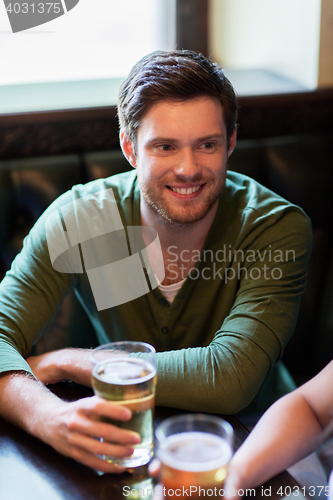 Image of happy friends drinking beer at bar or pub
