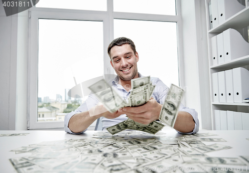 Image of happy businessman with heap of money in office