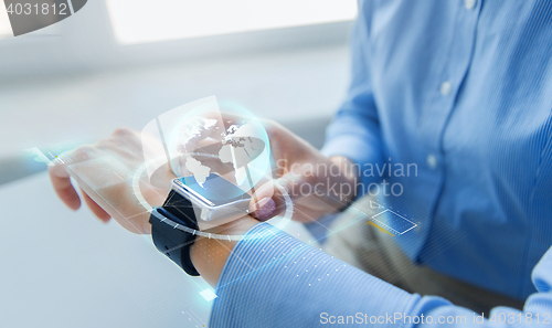 Image of close up of hands and globe hologram on smartwatch