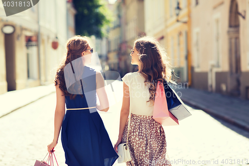 Image of happy women with shopping bags walking in city 