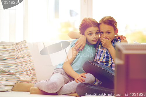 Image of scared little girls watching horror on tv at home