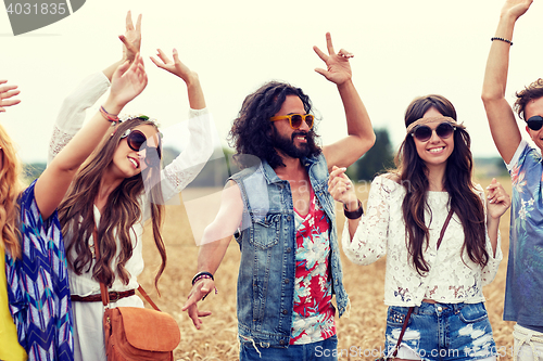 Image of happy young hippie friends dancing on cereal field