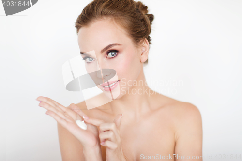 Image of happy young woman with moisturizing cream on hand