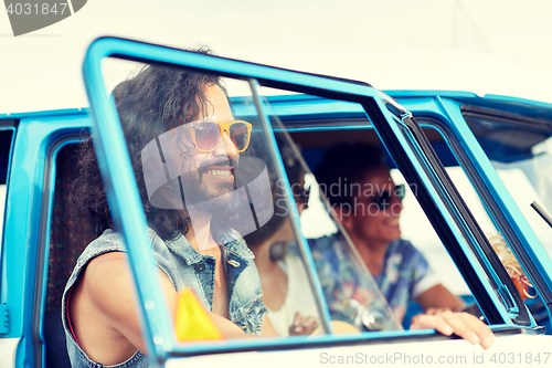 Image of smiling young hippie friends in minivan car