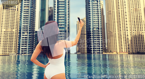 Image of woman taking selfie with smartphone over city pool